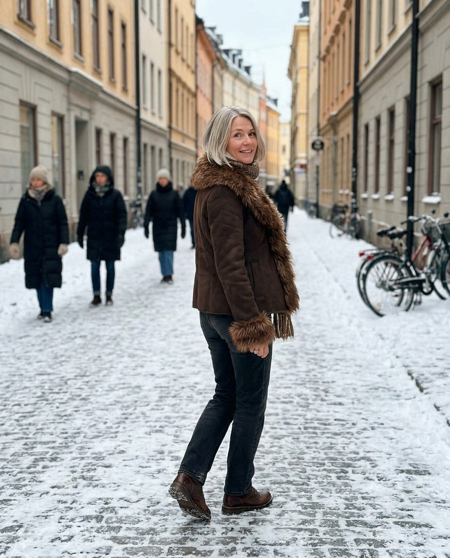 Nora, damjacka i mockalook med fuskpälskant i brun, stylinginspiration på en snöig gata
