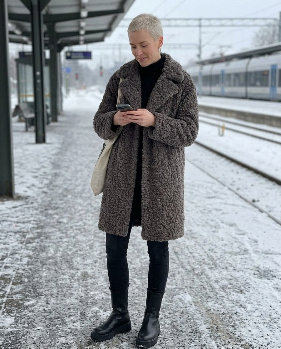 Alma, knälång kappa i lockig fuskpäls för dam i grå, stylinginspiration på en perron