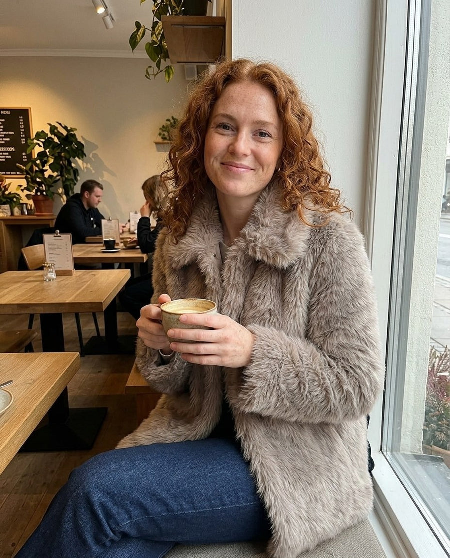 Freja, kort fuskpälsjacka för dam i gråbeige, stylinginspiration på ett kafé