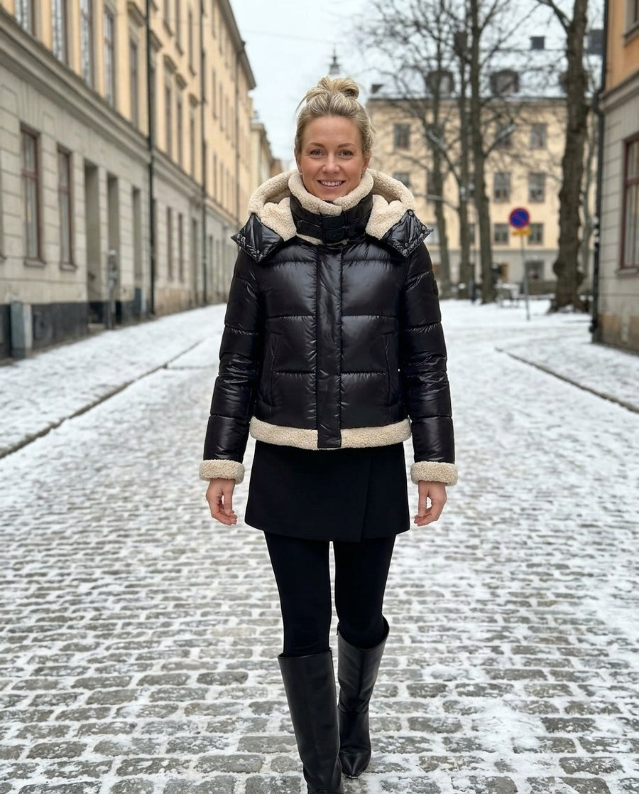 Ingrid, kort pufferjacka med teddyfoder för dam i svart, stylinginspiration på en snöig gata