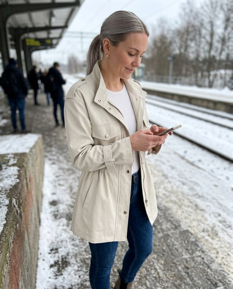Clarisse, kort trenchcoat för dam i vit, stylinginspiration på en perron