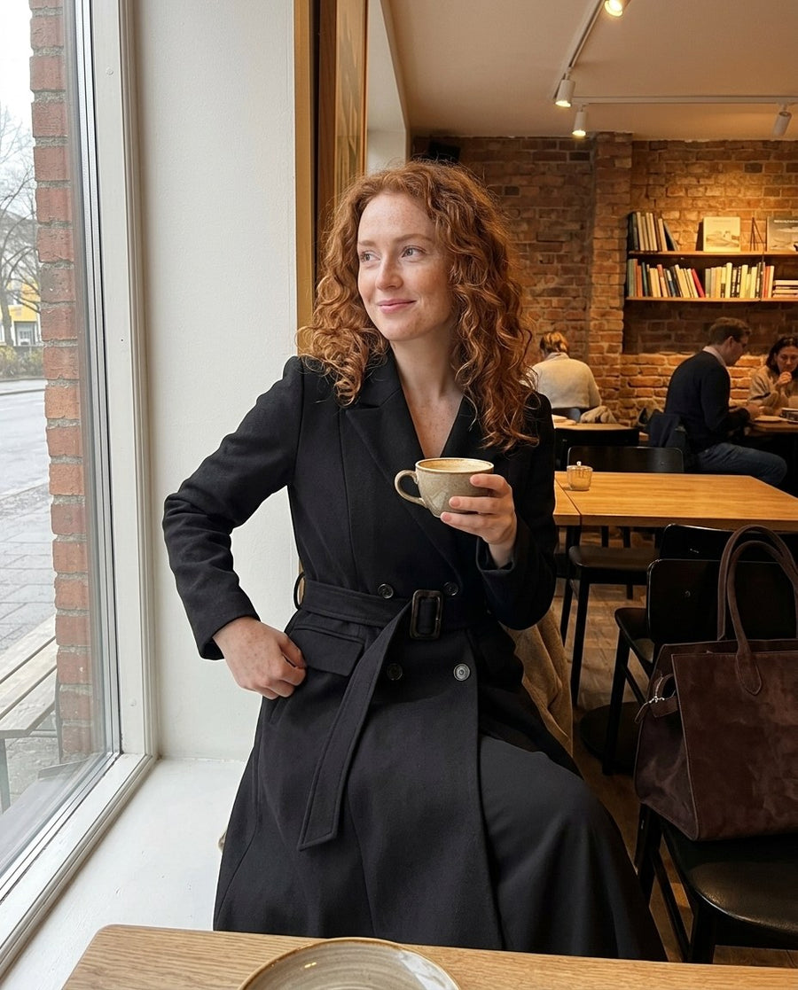 Kvinnors Lång Trenchcoat med Traditionell Dubbelknäppning, kvinnors lång trenchcoat med traditionell dubbelknäppning i svart, stylinginspiration på ett kafé