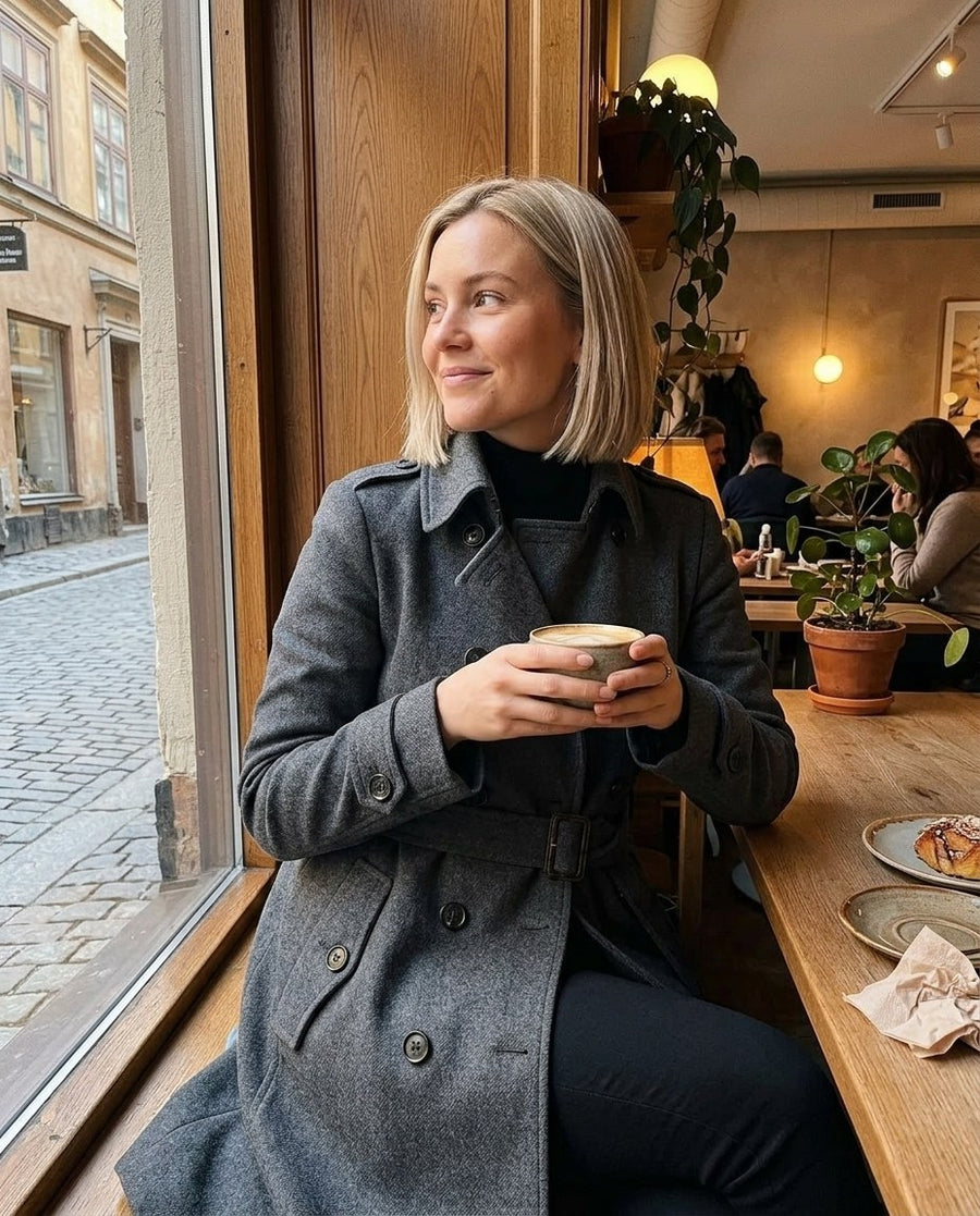 Alicia, lång midjesmal trenchcoat i mörkgrå, stylinginspiration på ett kafé