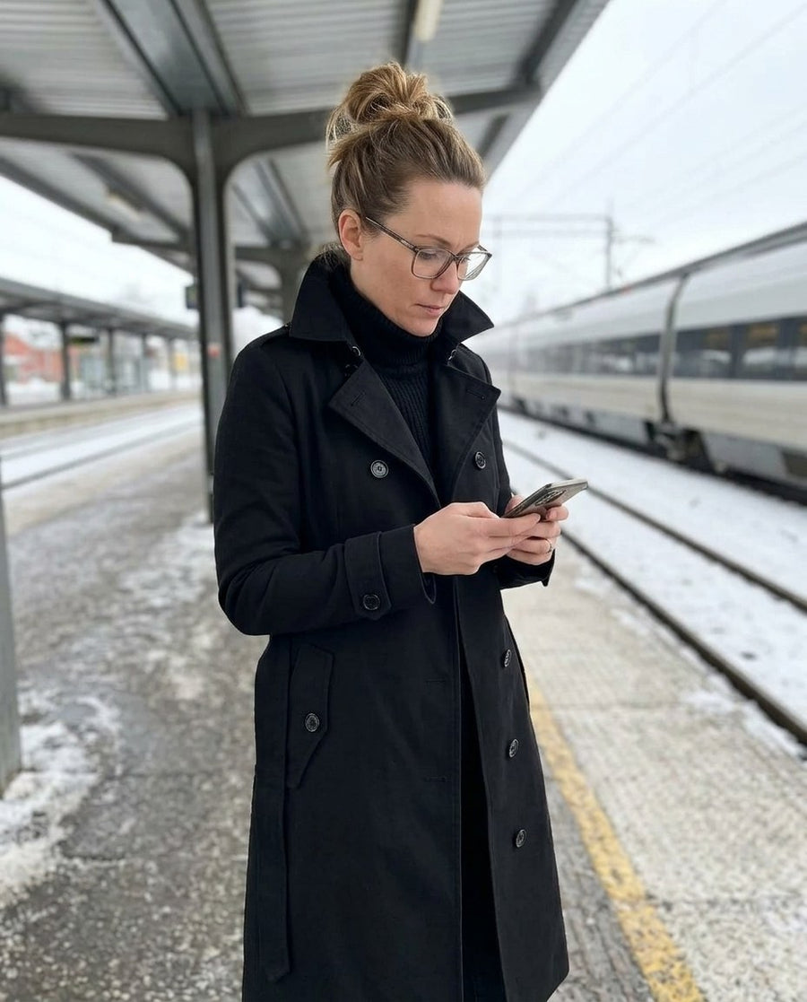 Alicia, lång midjesmal trenchcoat i svart, stylinginspiration på en perron