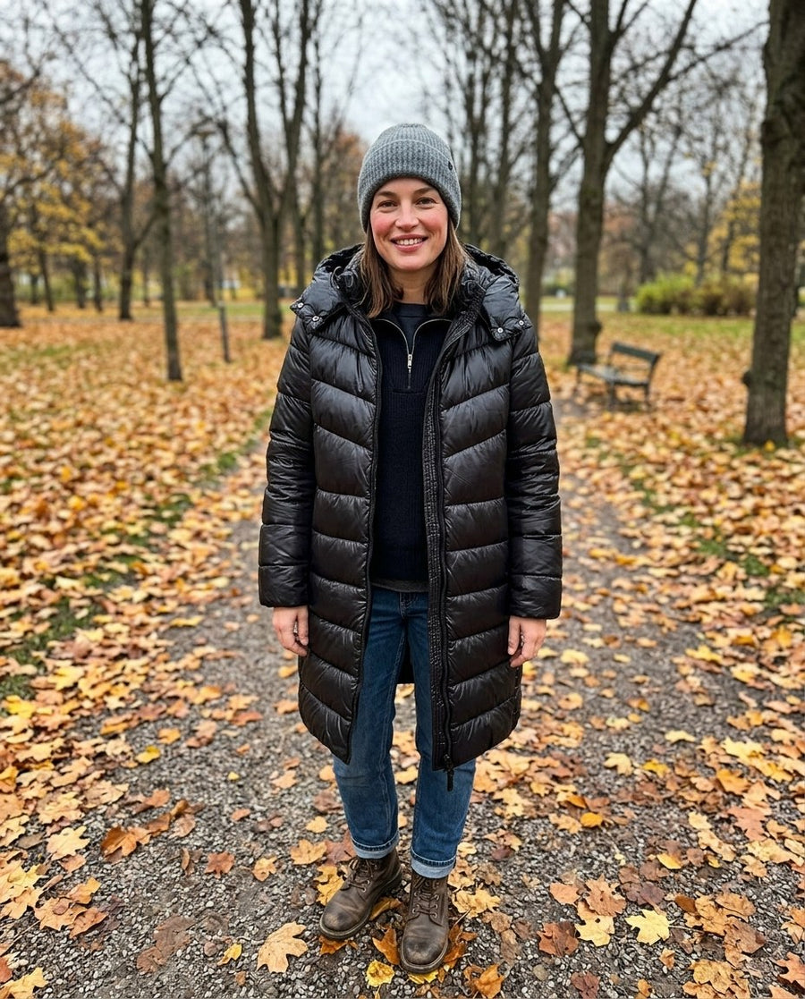 Vera, lång pufferkappa med huva för dam i svart, stylinginspiration i en höstpark